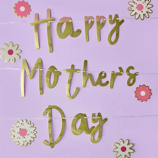 A gold Happy Mother’s Day banner decorated with pink and white floral cut‑outs on a pastel purple background.